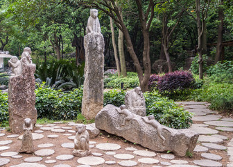 Guilin, China - May 11, 2010: Seven Star Park. Gray stone statue group of monkeys with green and...
