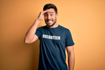 Young handsome man with beard volunteering wearing t-shirt with volunteer message stressed with...