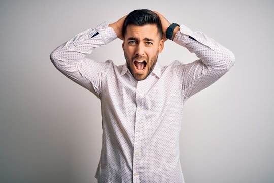 Young handsome man wearing elegant shirt standing over isolated white background Crazy and scared with hands on head, afraid and surprised of shock with open mouth