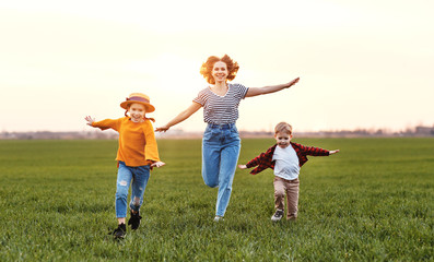 Fototapeta premium Happy woman with kids running in field.