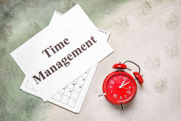 Alarm clock, calendar and paper with text TIME MANAGEMENT on table