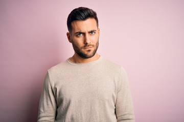 Young handsome man wearing casual sweater standing over isolated pink background skeptic and nervous, frowning upset because of problem. Negative person.