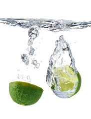 Falling of fresh cut lime into water against white background