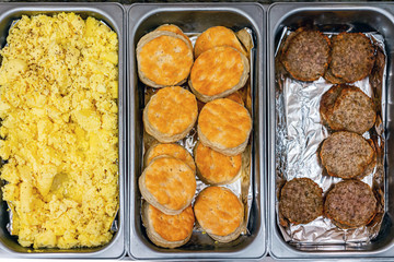 Fresh hot buffet tray flat top view of food scrambled eggs, biscuits and sausages in banquet, wedding, or restaurant inside for morning continental breakfast in hotel motel