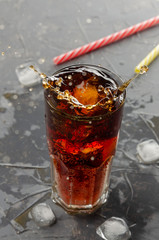 Ice cube droped in soda glass with splashing on the grey background