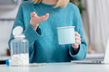 Woman with tablets next to computer at kitchen