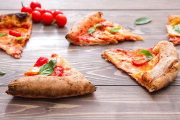Slices of delicious pizza Margherita on wooden background