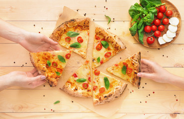 People taking slices of delicious pizza Margherita from table