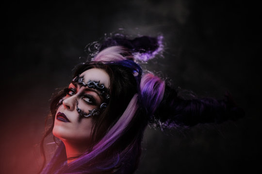 Close up photo of a mystic young girl in a magic creature cosplay, wearing dark banshee make-up and violet horns, looking devil