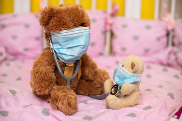 large teddy bear with phonendoscope in protective mask and small teddy bear in medical mask sit in cot. Coronovirus, quarantine, pandemic, flu, cold,illness. Medicine concept and health