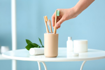 Woman taking wooden tooth brush from holder in bathroom