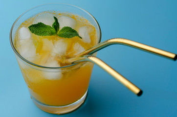 Fresh orange juice and a reusable tube on a background