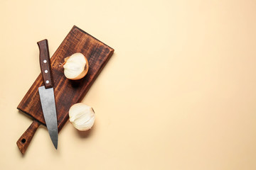 Cutting board, knife and fresh raw onion on color background