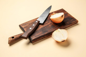 Cutting board, knife and fresh raw onion on color background