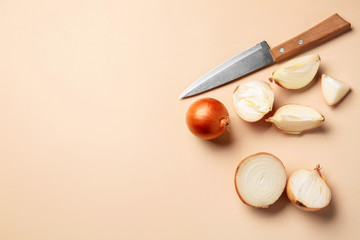 Fresh cut onion and knife on color background