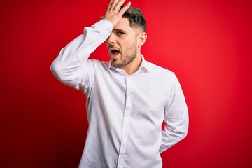 Young business man with blue eyes wearing elegant shirt standing over red isolated background...
