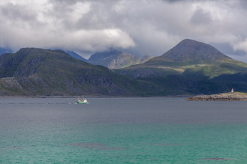 ship to visit fjords in Norway in polar day, midnight sun. A mystical fjord with dark clouds in Norway with mountains and fog hanging over the water