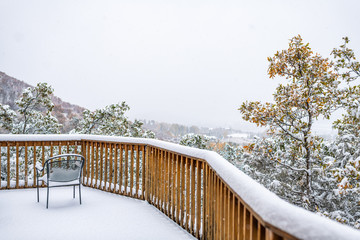 House home property real estate with view of floor and autumn foliage on trees with snow covering leaves and chair by window