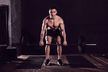 Fototapeta na wymiar Strong man lifting barbell in modern gym