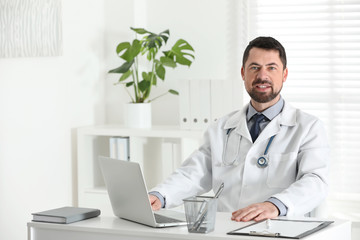 Fototapeta na wymiar Portrait of male doctor in white coat at workplace