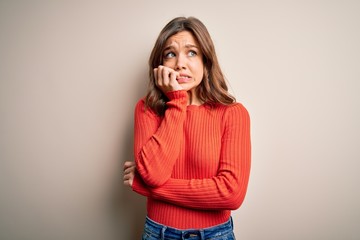 Young blonde girl wearing casual red sweater over isolated background looking stressed and nervous...