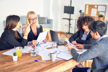 Group of business workers smiling happy and confident. Working together with smile on face  using laptop and speaking at the office