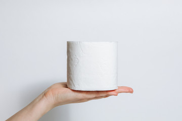 A roll of toilet paper in hand in case of an epidemic. COVID-19 coronavirus outbreak concept. Shortage due to buying panic. White background