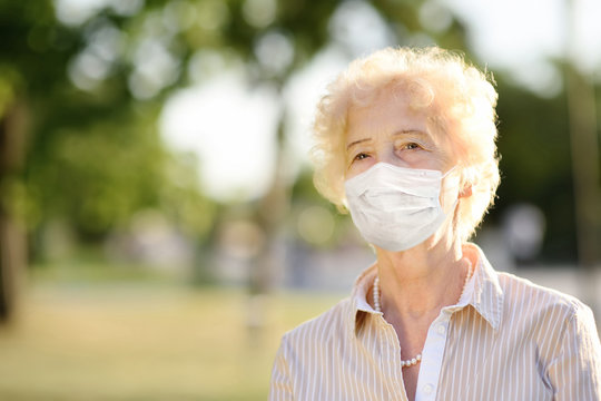 Outdoors portrait senior woman wearing disposable medical face mask. Safety in public place during coronavirus outbreak.