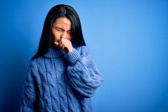 Young beautiful chinese woman wearing casual sweater over isolated blue background feeling unwell and coughing as symptom for cold or bronchitis. Health care concept.