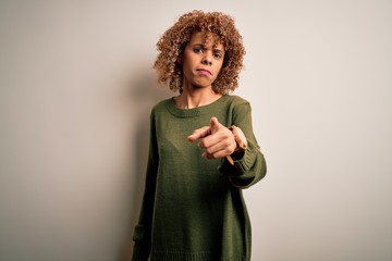 Beautiful african american woman with curly hair wearing casual sweater over white background pointing displeased and frustrated to the camera, angry and furious with you