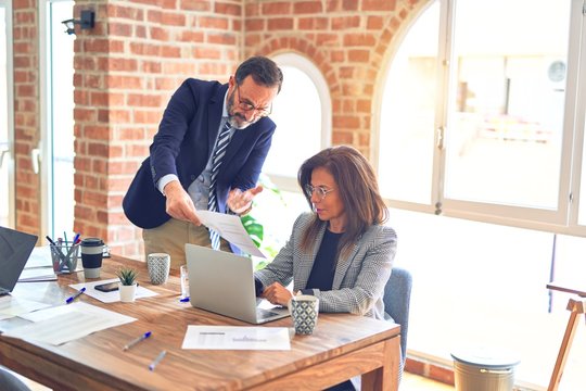 Two middle age business workers working together. Man bullying woman at the office