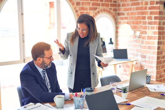 Two middle age business workers working together. Woman bullying man at the office