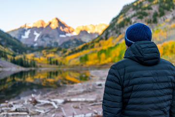 Maroon Bells lake at sunrise with man looking in Aspen, Colorado with rocky mountain peak in...