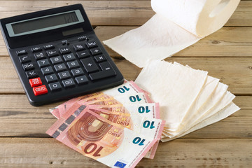 sheets and roll of toilet paper, calculator and euro money, on wooden background. concept