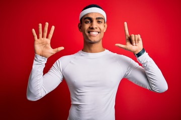 Young handsome african american sportsman wearing sportswear over red background showing and...