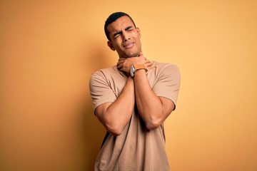 Obraz premium Young handsome african american man wearing casual t-shirt standing over yellow background shouting suffocate because painful strangle. Health problem. Asphyxiate and suicide concept.