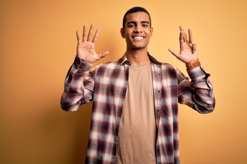 Young handsome african american man wearing casual shirt standing over yellow background showing...