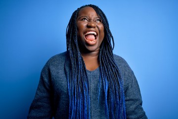 African american plus size woman with braids wearing casual sweater over blue background angry and...