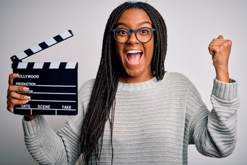 Young african american director girl filming a movie using clapboard over isolated background...