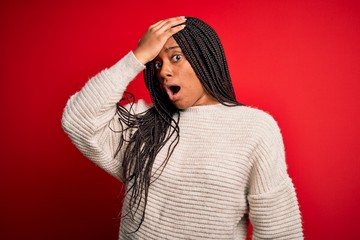 Young african american woman wearing casual winter sweater over red isolated background surprised...