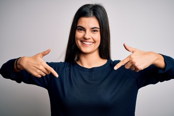 Young beautiful brunette woman wearing casual sweater standing over white background looking...