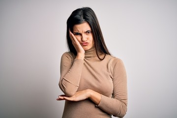 Young beautiful brunette woman wearing turtleneck sweater over white background thinking looking tired and bored with depression problems with crossed arms.