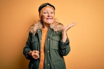 Senior beautiful grey-haired skier woman wearing snow sportswear and ski goggles smiling cheerful...