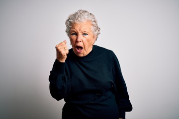 Senior beautiful woman wearing casual black sweater standing over isolated white background angry...