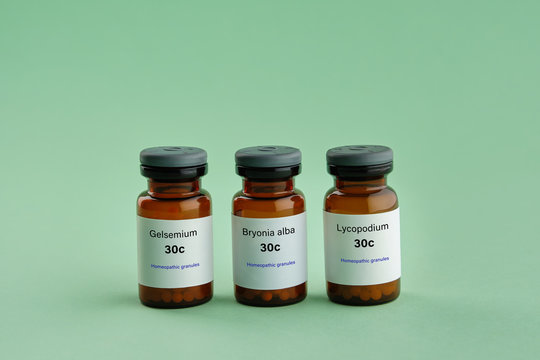 Bottles of homeopathic drugs - Gelsemium, Bryonia alba, Lycopodium - remedies recommended by homeopaths for treatment and prophylaxis of Coronavirus Covid-19 Infection. Green background.