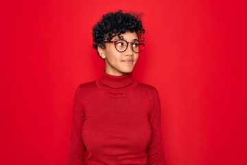 Obraz na płótnie Canvas Young beautiful african american afro woman wearing turtleneck sweater and glasses smiling looking to the side and staring away thinking.