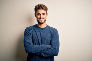 Young handsome man with beard wearing casual sweater standing over white background happy face...