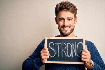 Young man holding blackboard with strong message standing over isolated white background with a happy face standing and smiling with a confident smile showing teeth