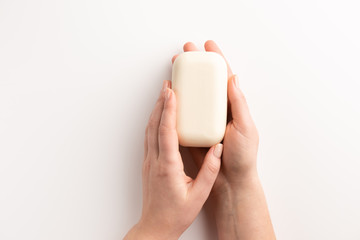 Female hands with bar of natural soap isolated, on white background. Flat lay, top view, copy space.