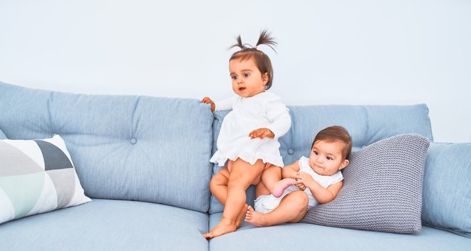 Beautiful infant happy girls playing together at home kindergarten sitting on the sofa